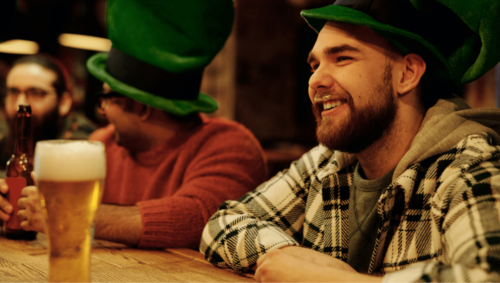 A person drinking beer in a green top hat