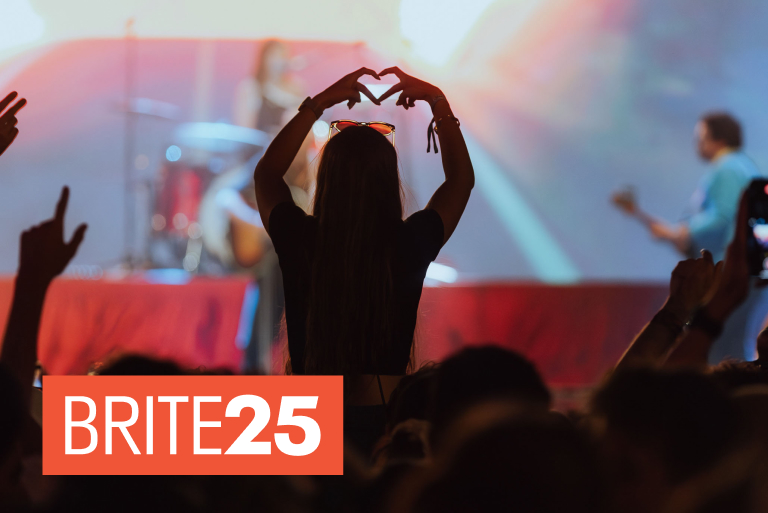 Female Bar Pop attendee makes love heart gesture with her hand in the crowd